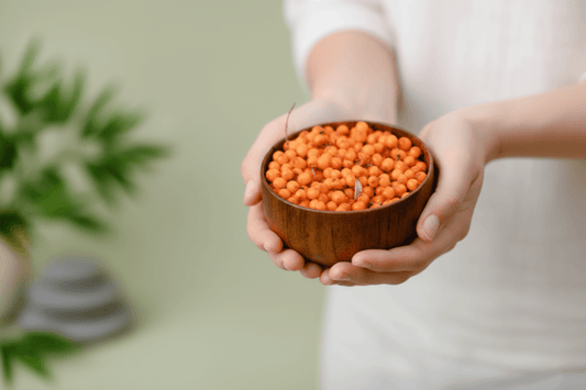A person holding a bowl of fresh, orange sea buckthorn berries, representing natural and organic ingredients.