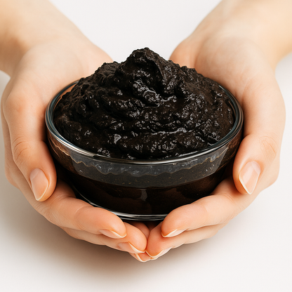 Hands holding a bowl of moor mud on a light background