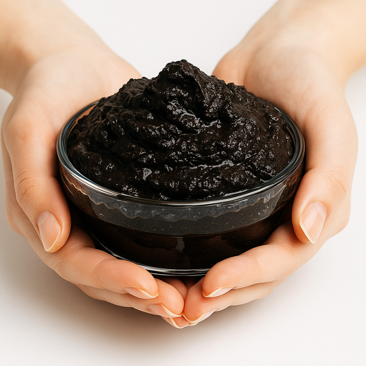 Hands holding a bowl of moor mud on a light background