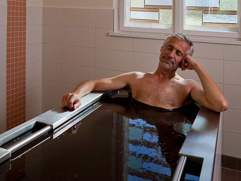 A peaceful man is relaxing in a warm Moor mud spa bath at a wellness retreat.
